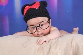 baby in glasses and a black hat on photoshoot