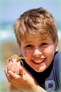 boy with a small crab on the beach close up