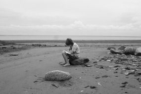 Sad child reading on a stone