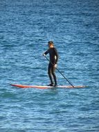 sporty man rowing on the surf in ocean