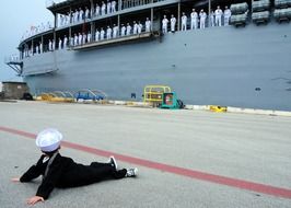 child in a marine costume on the pier near a large ship