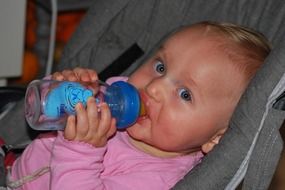 baby drinks from a bottle