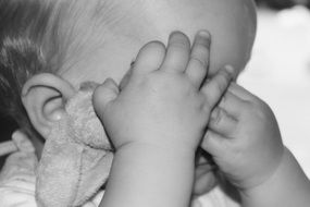 little child covers his face with his hands