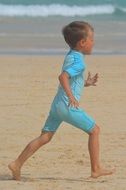 boy runs along the sand on a sunny day