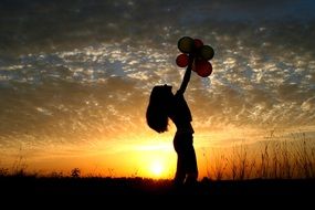 girl with balloons at sunset background