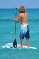 Rear view of a man on a blackboard with a paddle on the water