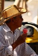 a man in a straw hat eats sorbet