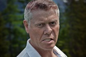 Portrait of angry man at blurred background with the plants