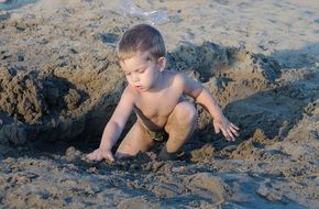 naked child plays in the sand