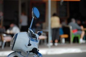 white scooter stands on the background of the cafe