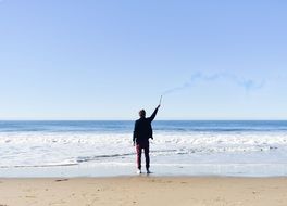 man on the beach with smoke signal