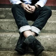 male person sits on steps in winter boots