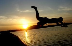 silhouette of a man jumping into the water