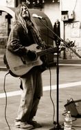 Black and white picture of a street musician with a guitar and a microphone