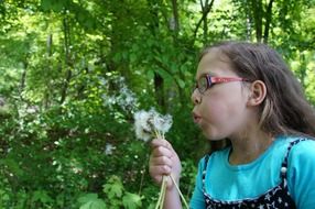 girl blowing a bouquet of dandelions