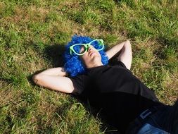 a man in a blue wig and sunglasses on green grass