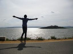 silhouette of a man on the riverside with arms outstretched