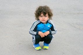 portrait of curly-haired boy with blue eyes in a tracksuit