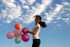 girl with balloons on a background of clouds