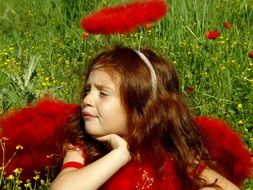 red-haired girl in a bright fantasy costume among the green meadow