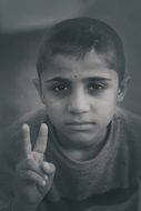 black and white image of a young man with a victory symbol