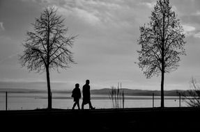 two silhouettes strolling by the lake