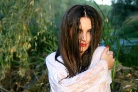 seductive girl with long hair concealing the face on the background of nature lake