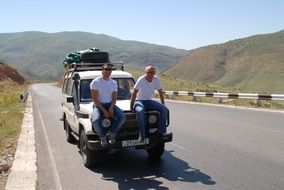 men sit on the hood of a jeep in America