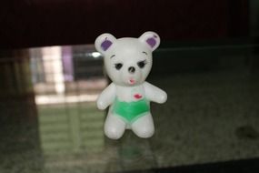 white toy bear in green pants