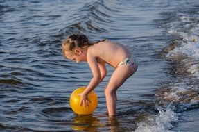 little girl with a yellow ball on the river