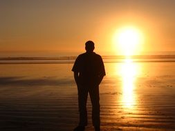 man on the background of a bright strip of sun at sunset