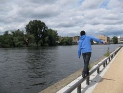 a man walks along the parapet near the river