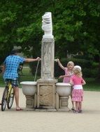 children and a man stand near the fountain