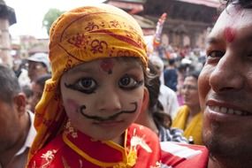 child in bright makeup at a festival in Nepal