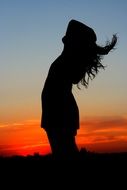 silhouette of a girl on a background of clouds at sunset