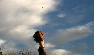 girl against the blue sky and flying birds