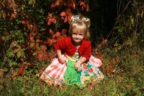 a child in a dress on a background of autumn leaves