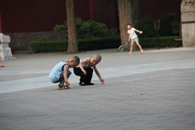two boys draw with chalk on the asphalt, china