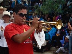 mature man plays trumpet on carnival, peru, cajamarca