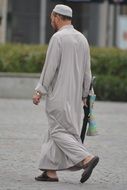 muslim man in long clothes walks down the street