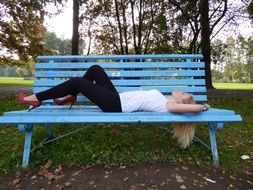 sexy girl lays down on bench in park