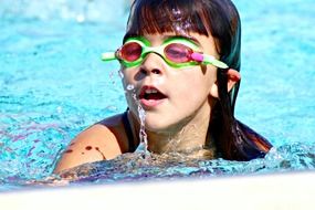 girl in green swimming goggles in the pool
