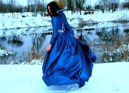 girl in a long blue dress by the winter river