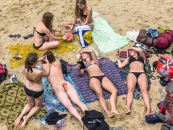 girls in swimsuits sunbathe on the beach