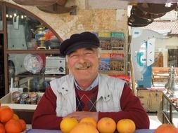 happy senior seller with oranges on market stall, turkey
