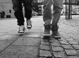 male legs are walking along a paved road