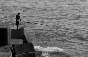 angler with a telescopic fishing rod on concrete blocks