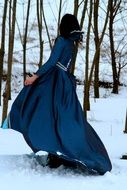 back view of girl princess in a blue dress walking on the snow