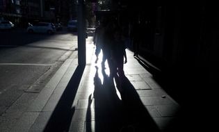 Shadows of people walking along the street at night