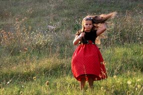 girl in a red dress on a green flower meadow